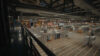 Blick ins REWE Logistikzentrum mit Regalen, Paletten und Mitarbeitenden bei der Arbeit in einer großen Lagerhalle.